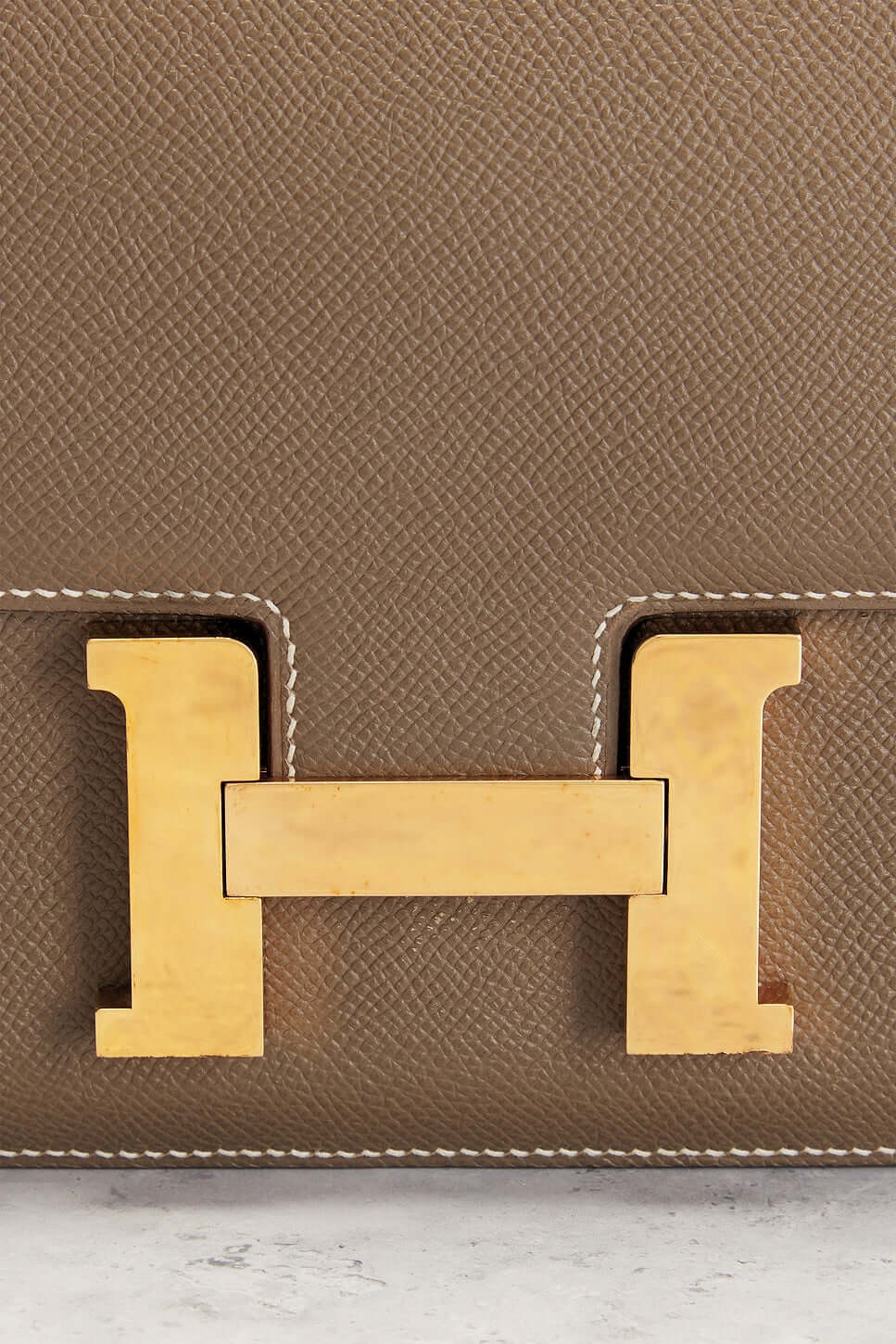 Hermès Constance Mini beige luxury bag for women featuring iconic gold H-shaped clasp, a timeless fashion statement.