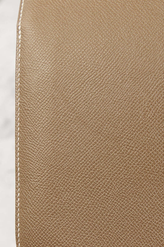 Close-up view of luxurious beige leather texture showcasing high quality finish of Hermès Constance Mini designer handbag.