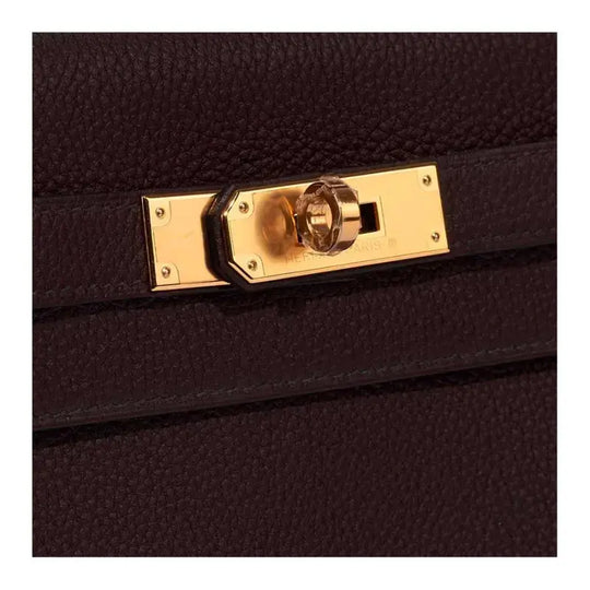 Close-up of Hermès luxury bag clasp in gold hardware against textured black leather, showcasing high-quality craftsmanship.