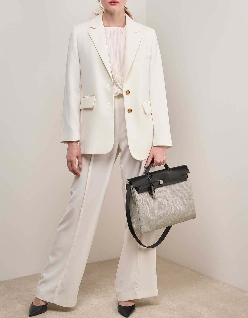 Model showcasing a luxury bag for women, a stylish handbag featuring a gradient design, complementing an elegant suit.