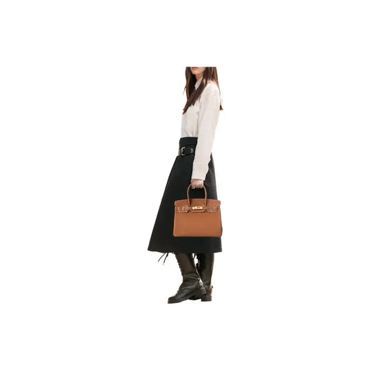 Hermes Birkin 25 brown tote bag in togo leather held by a woman in a stylish outfit, a timeless luxury bag for women.
