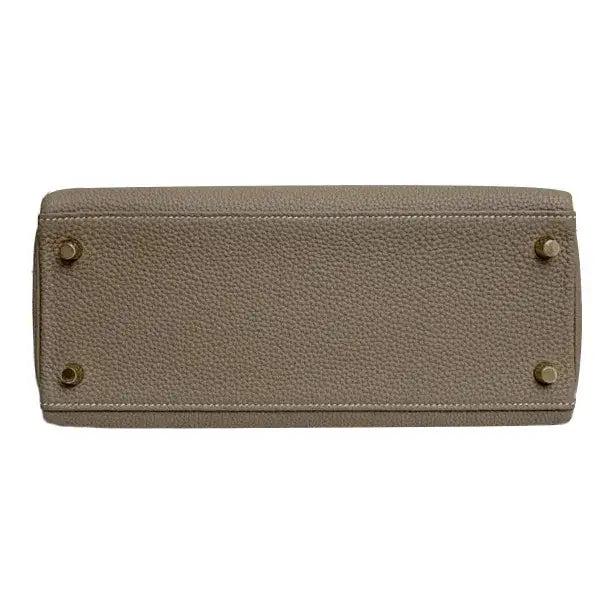 HERMES Kelly 25 elegant gray Togo leather handbag base featuring protective feet, a high quality luxury bag for women.