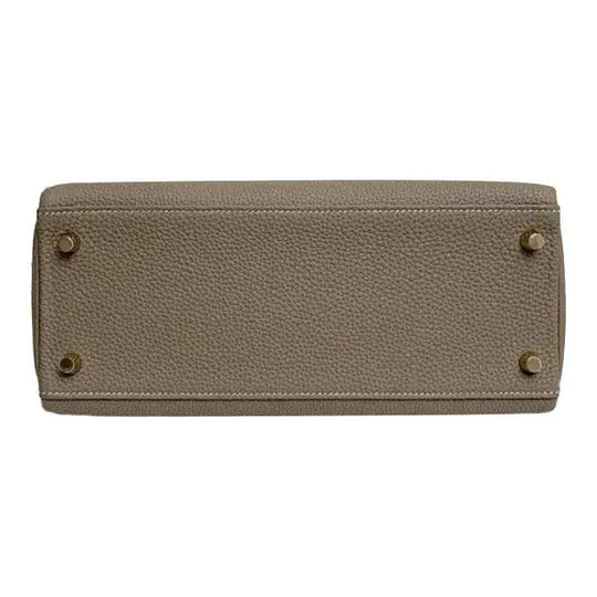 HERMES Kelly 25 elegant gray Togo leather handbag base featuring protective feet, a high quality luxury bag for women.