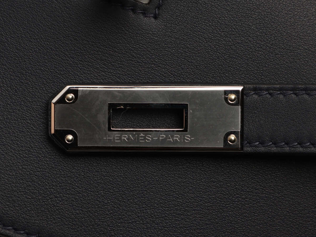 Hermès Paris metal detail on luxurious black leather, showcasing craftsmanship of a designer handbag, perfect for elevated style.