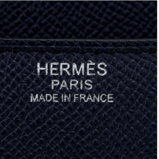 Hermès Paris logo embossed on black leather, symbolizing luxury bag craftsmanship and timeless fashion.