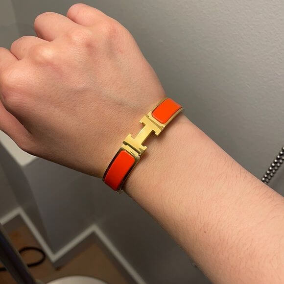 Hermes Clic HH bracelet 12MM in vibrant orange with gold H clasp, a high-quality fashion accessory perfect for stylish layering.